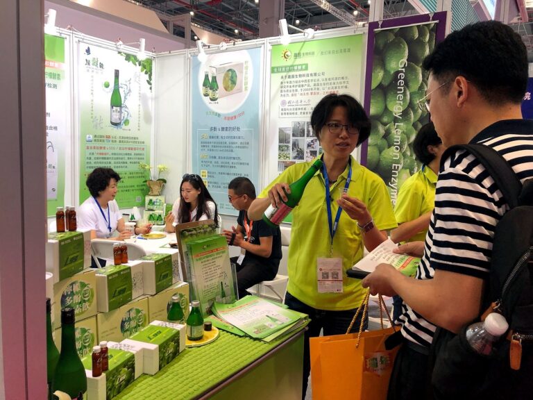 穿萊姆綠 POLO 衫的工作人員倒綠甦能檸檬酵素給來賓試喝