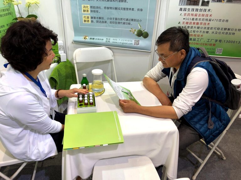 工作人員向來賓展示一盒咖啡色試飲小瓶，來賓正在看 DM